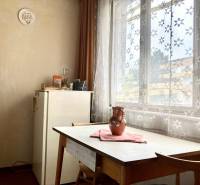 Dining room in a 3-room apartment with a table, chairs, and curtains with a floral pattern.