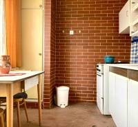 A kitchen in a 3-room apartment with red brick cladding and a wooden table.
