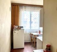 A kitchen in a 3-room apartment with a wooden decor floor, simple furnishings, and a window.