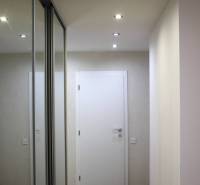 A hallway with a built-in mirrored wardrobe and a wooden decor floor in a 3-room apartment.