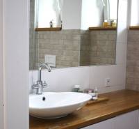A bathroom with a large mirror and a sink on a wooden decor in a 3-room apartment.