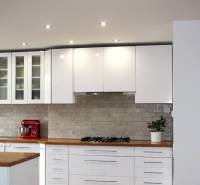 A kitchen in a 3-room apartment with white cabinets and a wooden decor countertop.