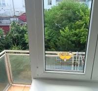 A view from a 3-room apartment with windows and a balcony overlooking a green courtyard.