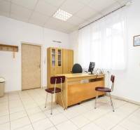 An office with wooden furniture, a computer, and decorations on the walls, tiled floor.