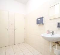 Office with a sink, dispensers, and a mirror. White tiles, light floor.