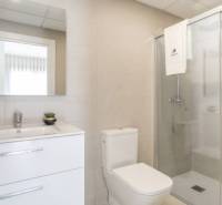 Bathroom of a holiday apartment with a toilet, sink, and shower.