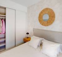 Bedroom in a holiday apartment with a bed, built-in wardrobe, and a mirror on the wall.