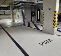Underground parking lot with numbered spaces, security features, and lighting.