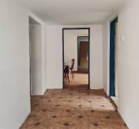 A hallway in a family house with tiles and furniture in the background.
