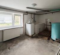 Technical room with a washing machine and a storage tank in a family house. Floor with wood decor.
