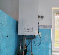 Gas boiler in a family house with blue tiles and a window.