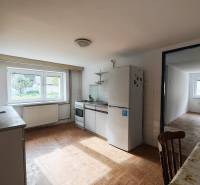 A kitchen in a family house with a wooden decor floor, equipped with appliances and a dining table.