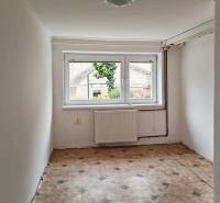 Small room with light walls, a large window, and patterned flooring in a family house.