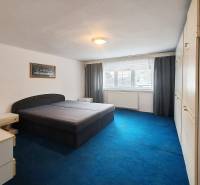 A bedroom in a family house with a large bed, a blue carpet, and a built-in wardrobe.