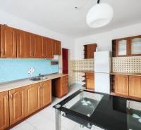 A family house kitchen with wooden cabinets, white tiles, and blue wall tiles.