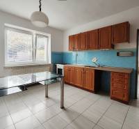 A kitchen in a family house with white tiles and wooden cabinets, glass table.