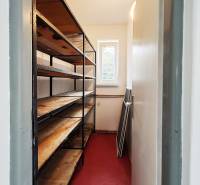A narrow storage space in a family house with shelves and a red floor.