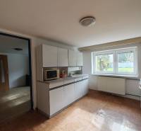 A kitchen in a family house with a wooden decor floor and a view of the garden.