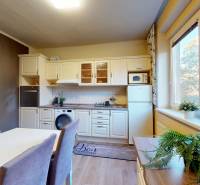 A kitchen in a 2-room apartment with a dining table, flowers, and a window with a view.