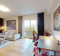Living room in a two-room apartment with a sofa, a desk, and a floor with a wooden decor.