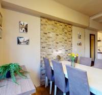 Dining area in a 2-room apartment with a wood-patterned floor and a decorative wall.