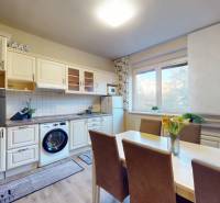 Kitchen in a 2-room apartment, white wooden cabinets, floor with wood decor, dining table.
