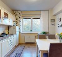 A kitchen in a 2-room apartment with a wooden decor floor, a dining table, and flowers.