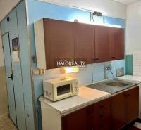 A kitchen with older cabinets, a microwave, and a stove in a 4-room apartment.
