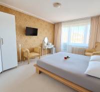 A bedroom in a 3-room apartment with elegant furniture, golden wallpaper, and a white carpet.