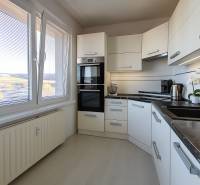The kitchen in a 3-room apartment with a wooden decor floor, light kitchen cabinets.