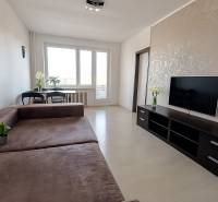 Living room in a 3-room apartment with a large sofa, TV, and flooring with a wooden decor.
