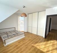 A bedroom in a family house with a bed, built-in wardrobe, and floor with wood decor.