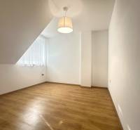 A room in a family house with a wood-patterned floor, a simple lamp, and a large window.