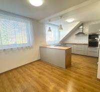 A kitchen in a family house with a wooden decor floor and light curtains on the windows.