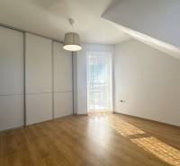 Interior of a building with wood-patterned flooring, a built-in wardrobe, and a window with a blind.