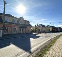A street with shops in Bolešov, next to a family house, in daylight.