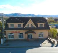 A family house in Bolešov with a shop on the ground floor and a mountain backdrop.