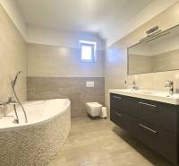 A bathroom with a bathtub, double sink, and mirror in a family house.