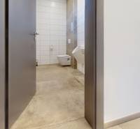 Interior of commercial premises with a toilet, white tiles and neutral flooring.