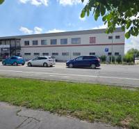 Commercial premises on Strojárenská Street in Trnava, with parking and cyclist.