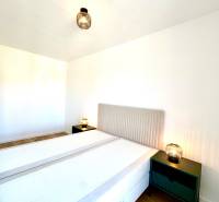 A bedroom in a two-room apartment with a wooden decor floor and nightstands.