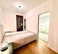 A bedroom with a bed, nightstands, and a wooden decor floor in a two-room apartment.