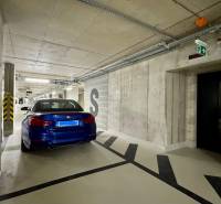 Underground parking lot with a blue car and escape signs.