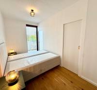 Bedroom in a 2-room apartment with a bed, lamps, and a floor with a wooden decor.