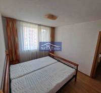 Bedroom in a 2-room apartment with a bed, curtains, and a wooden decor floor.