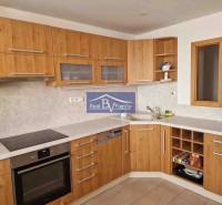 A kitchen in a 2-room apartment with wooden cabinets and a kitchen counter.