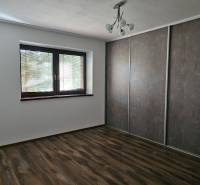 A room in a family house with a wooden decor floor and a large built-in wardrobe.