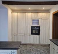 A kitchen with a dark countertop and a built-in oven, floor with wood decor.