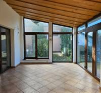 A room in a family house with large windows and tiles, view of the garden.