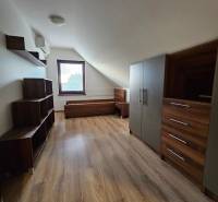 Attic of a family house with furniture, wood-patterned flooring, and a window.